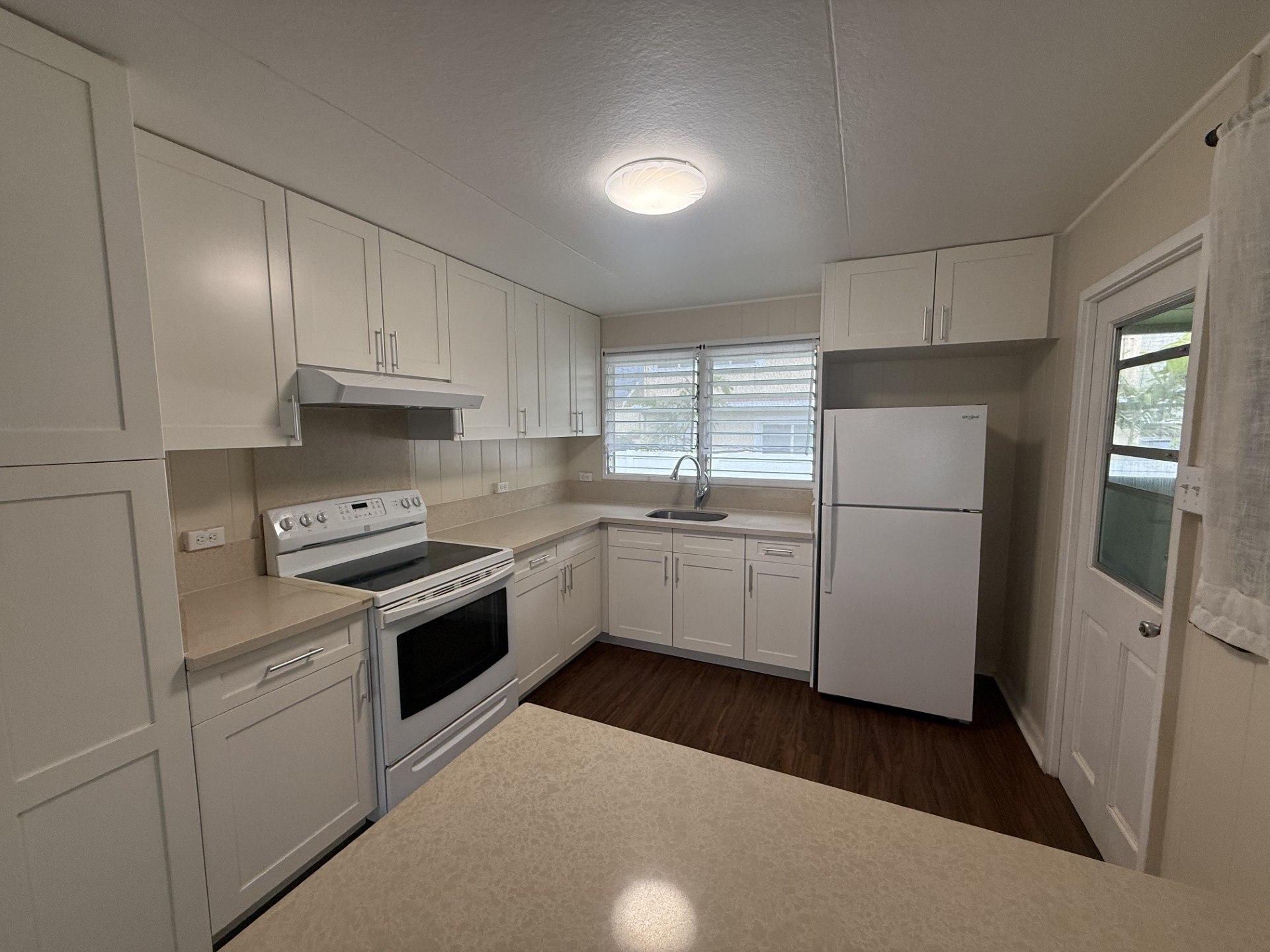 A kitchen with white appliances and cabinets.